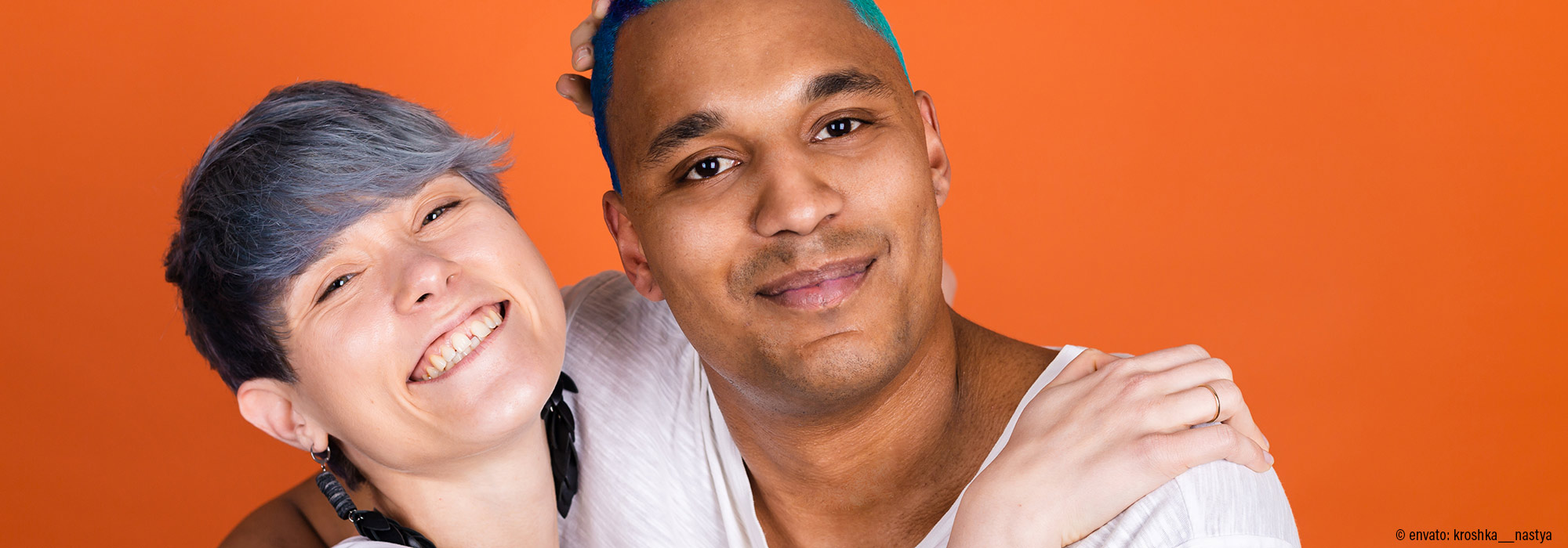 Zwei Menschen in glücklicher Partnerschaft umarmen sich vor orangefarbenem Hintergrund - Fachmodul Autismus und Sexualität (k)ein Problem Lebenshilfe