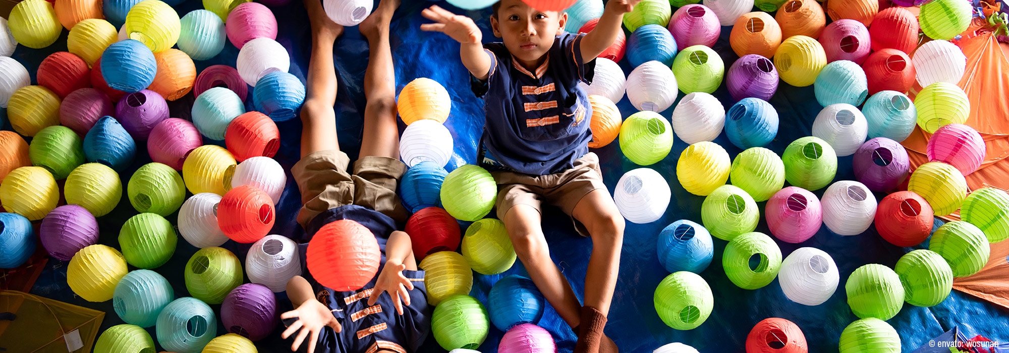 Kinder in blauen Shirts umgeben von hunderten bunten Papierlaternen in allen Farben - Fachmodul Sensorische Integration Kinder Spektrum ganzheitlich begleiten Lebenshilfe Alfeld