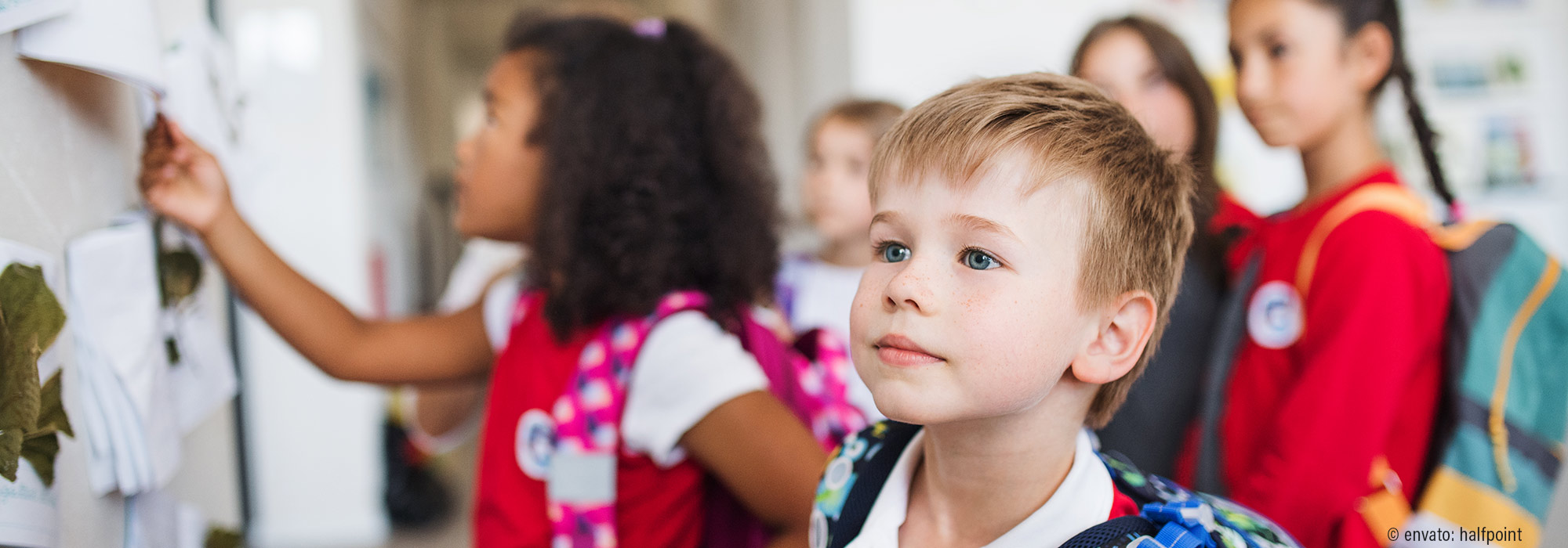 Schulanfänger mit buntem Ranzen und Mitschüler im Hintergrund - Fachmodul Übergangsgestaltung Kita - Schule - Lebenshilfe Alfeld